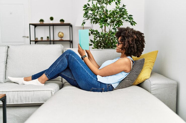 woman reading book on sofa