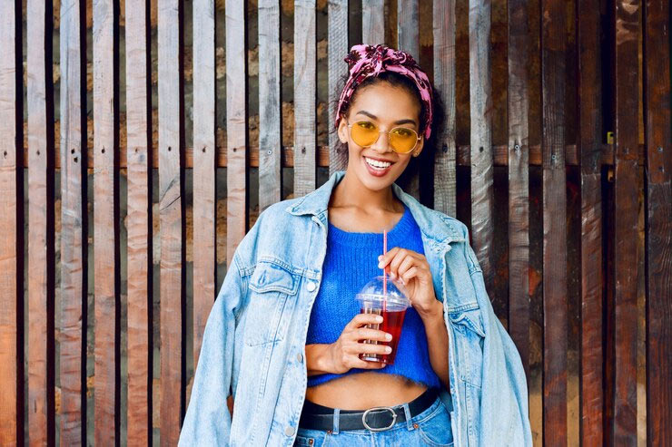 smiling woman in denim holding drink