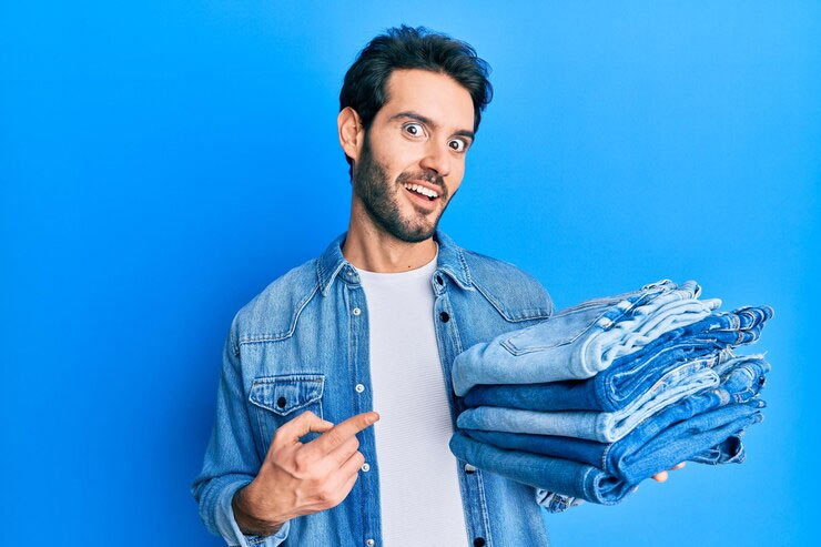 man holding a stack of folded jeans