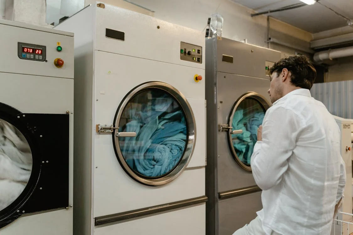 man washing clothes in laundromat