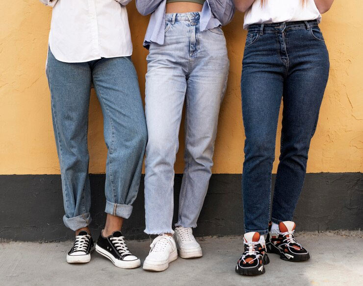 three women wearing jeans and sneakers.